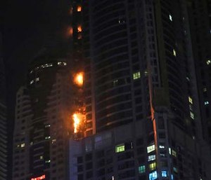 The high-rise residential tower has caught fire in the middle of the night, sending plumes of black smoke into the air and debris falling below.