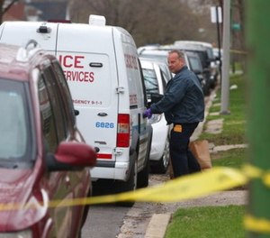 An investigator opens the door of a vehicle outside a home on the South Side of Chicago, Monday morning, April 10, 2017, after Cook County Circuit Court Raymond Myles was shot to death outside his home. (Zbigniew Bzdak/Chicago Tribune via AP)