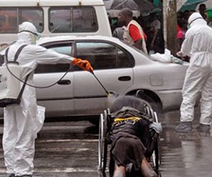 Health workers spray the body of an amputee suspected of dying from the Ebola virus with disinfectant in Liberia.