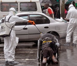 Health workers spray the body of an amputee suspected of dying from the Ebola virus with disinfectant in Liberia. (AP Photo/Abbas Dulleh, File)