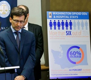 Washington Attorney General Bob Ferguson, second from left, listens to a question, Thursday, Sept. 28, 2017, in Seattle, as he stands near a chart detailing increases in overdoses and hospital stays relating to opioid use in Washington state.