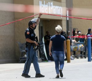 An employee crosses into the crime scene following a shooting at a Walmart in El Paso, Texas, Saturday, Aug. 3, 2019.
