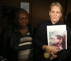 Kelly Adams holds up a photo of her face following the attack in court.