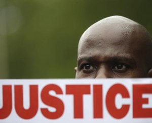 In this July 18, 2015 file photo, a demonstrator holds a sign calling for justice during a rally in New York were several hundred people rallied outside the federal courthouse in Brooklyn to demand action in the fatal chokehold death of Eric Garner by a white police officer.