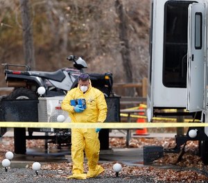 An investigator emerges with evidence from a trailer in a park along Clear Creek in which the body of a 63-year-old man was found Tuesday, Oct. 31, 2017, in Golden, Colo.