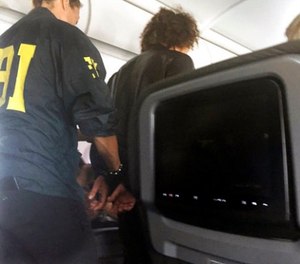 In this photo provided by Donna Basden, a man is escorted off an American Airlines flight after it landed in Honolulu, Friday, May 19, 2017. Federal agents met the plane from Los Angeles when it landed in Honolulu and took the man into custody. (Donna Basden via AP)