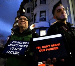In this Tuesday, Feb. 23, 2016, file photo, demonstrators Peter Brockmann, of Northborough, Mass., left, and Chris Gladney, of Boston, right, display iPads with messages on their screens outside an Apple store in Boston.