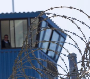In this Aug. 17, 2011, file photo, concertina wire and a guard tower are seen at Pelican Bay State Prison near Crescent City, Calif.