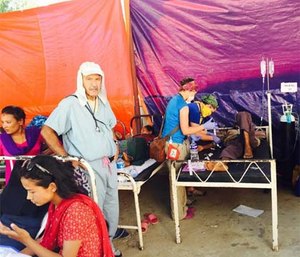 Paramedic Julie Beach, wearing a yellow face scarf, cares for a patient in a field hospital after the Nepal earthquake.