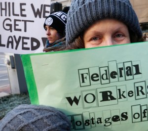 Esther Anastasia holds a sign during a protest rally with government workers and their supporters in Boston, Friday, Jan.11, 2019. The workers rallied with Democratic U.S. Sen. Ed Markey and other supporters to urge that President Donald Trump put an end to the shutdown so they can get back to work. (AP Photo/Michael Dwyer)