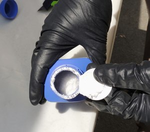 In this June 27, 2016 photo provided by the Royal Canadian Mounted Police, a member of the RCMP opens a printer ink bottle containing the opioid carfentanil imported from China, in Vancouver.