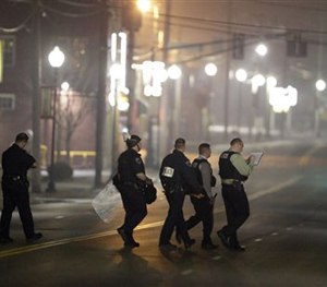 Police canvass the area as they investigate the scene where two police officers were shot outside the Ferguson Police Department Thursday, March 12, 2015, in Ferguson, Mo. (AP Image)