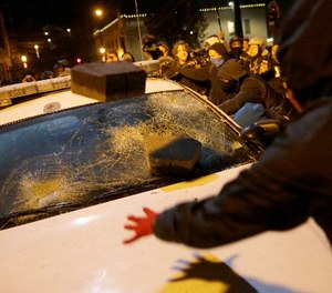 In this Nov. 25, 2014 file photo, protesters vandalize a police vehicle outside of Ferguson city hall in Ferguson, Mo.