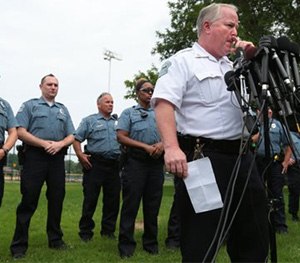 This photo shows Ferguson Police Chief Tom Jackson surrounded by his officers as he answers questions at a news conference in Forestwood Park.