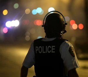 A law enforcement officer watches Sunday, Aug. 17, 2014, after tear gas was fired to disperse a crowd protesting the shooting of teenager Michael Brown last Saturday in Ferguson, Mo. (AP Image)