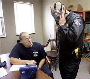 Alton, Ill., Fire Department engineer Bob Eichen, left, uses a machine to run a series of five tests on the gas mask of Alton Police officer Michael Beaber, right, at the Don Twichell Memorial Fire Station in Alton, Monday Nov. 10, 2014. (AP Image)