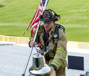 A firefighter rings the bell to remember the fallen during the 2017 9/11 Memorial Stair Climb at Lambeau Field. (Photo courtesy of Pierce Manufacturing)