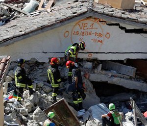 Rescuers mark a building with paint signaling the date and time of start and end of the search operation on that building, following Wednesday's earthquake in Pescara Del Tronto, Italy, Thursday, Aug. 25, 2016.
