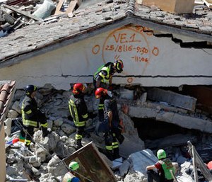 Rescuers mark a building with paint signaling the date and time of start and end of the search operation on that building, following Wednesday's earthquake in Pescara Del Tronto, Italy, Thursday, Aug. 25, 2016.