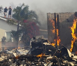 Two people were found dead and scores of houses burned in a pair of wildfires that stretched across more than 100 square miles of Southern California. (Photo/AP)