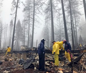 After a brief delay to let a downpour pass, volunteers resume their search for human remains at a mobile home park. (Photo/AP)