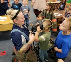 West Virginia firefighter Wendi Wentzell-Cuc shows a child her face mask during Fire Prevention Week. She and the department signed LION's