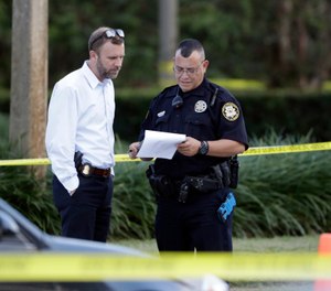 Law enforcement officers look over papers out in front of a SunTrust bank, Wednesday, Jan. 23, 2019, in Sebring, Fla., where authorities say five people were shot and killed (AP Photo/Chris O'Meara)