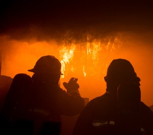 A firefighter with the Gowen Field Fire Department instructs a fellow firefighter on how to recognize the signs of flashover during a training in a specialized mobile burn trailer.