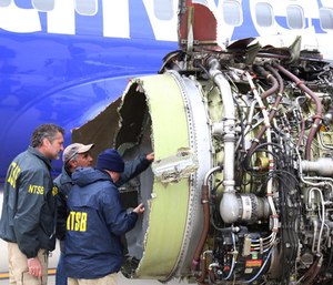 National Transportation Safety Board investigators examine damage to the engine of the Southwest Airlines plane that made an emergency landing at Philadelphia International Airport in Philadelphia on Tuesday.