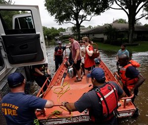 Members of the Houston and Webster fire departments help residents evacuate through the floodwaters surrounding their homes.