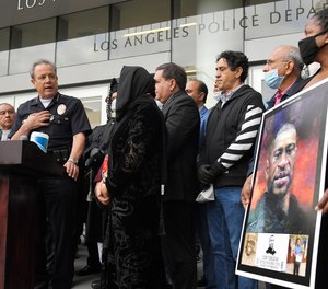 In this June 5, 2020, file photo, Los Angeles police chief Michel Moore, left, speaks as someone holds up a portrait of George Floyd during a vigil with members of professional associations and the interfaith community at Los Angeles Police Department headquarters in Los Angeles. (AP Photo/Mark J. Terrill, File)