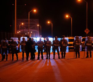 Police line up as protesters attempt to take over the Crescent City Connection bridge, which spans the Mississippi River in New Orleans, Wednesday, June 3, 2020, during a protest over the May 25 death of George Floyd.