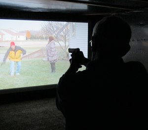 Mark Tulloch, of Kettering, Ohio, takes aim in a firearms training simulator at the Clark County Fair on Wednesday, July 26, 2017, in Springfield, Ohio.