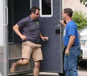 Subway restaurant spokesman Jared Fogle leaves a mobile evidence-gathering lab outside of his home as Indianapolis Metropolitan Police Department Det. Darin Odier holds the door. (AP Image)