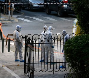 Greek forensic experts search at the scene after an explosion outside the Orthodox church of Agios Dionysios in the upscale Kolonaki area of Athens, Thursday, Dec. 27, 2018. Police in Greece say an officer has been injured in a small explosion outside a church in central Athens while responding to a call to investigate a suspicious package.