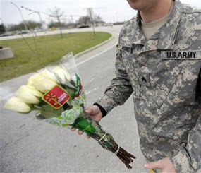 An unidentified soldier holds flowers dropped off at Fort Hood's main gate for shooting victims, Thursday, April 3, 2014, in Fort Hood, Texas.