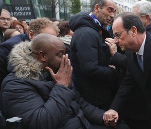 French President Francois Hollande speaks with a victim after unveiling a commemorative plaque outside the Stade de France stadium, in Saint-Denis, near Paris, France.