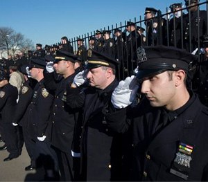 Police officers salute as the hearse of New York city police officer Rafael Ramos drives along his funeral procession route in the Glendale section of Queens.