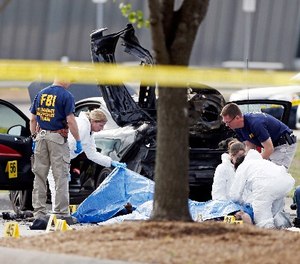 In this May 4, 2015 file photo, FBI crime scene investigators document the area around two deceased gunmen and their vehicle outside the Curtis Culwell Center in Garland, Texas.