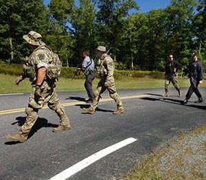 Members of the Pennsylvania State Police and law enforcement conservation officers with the Pennsylvania Game Commission walk from the state police barracks to a wooded area across the street on Route 402 to investigate near where two Pennsulvania State troopers were ambushed Friday, on Sunday, Sept. 14, 2014, in Blooming Grove Township, Pa.
