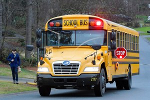 A Cobb County School bus moves on street Friday, March 13, 2020, in Kennesaw, Ga. Georgia's second-largest school district on Thursday, July 14, 2022 approved a policy allowing some employees who aren't certified police officers carry guns in schools, but excluded teachers from those who can be armed.