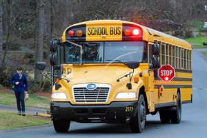 A Cobb County School bus moves on street Friday, March 13, 2020, in Kennesaw, Ga. Georgia's second-largest school district on Thursday, July 14, 2022 approved a policy allowing some employees who aren't certified police officers carry guns in schools, but excluded teachers from those who can be armed.