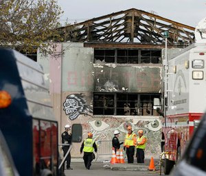 This Dec. 7, 2016 file photo members of the Alameda County Sheriff's Office stand outside the warehouse called the Ghost Ship the site of a fire, in Oakland, Calif.