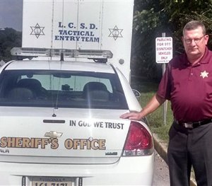 Lee County, Va., Sheriff Gary Parsons stands next to a patrol car that displays an 