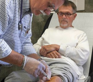 In this Sept. 12, 2012, file photo Dr. David Mathis gives a cortisone shot to the knee of inmate Edwin Bergman at the California Medical Facility in Vacaville, Calif.