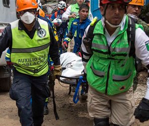 Members of a rescue team carry a body recovered the site of a mudslide on the outskirts of Guatemala City.