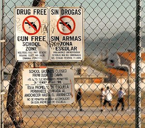 Drug and gun free school zone signs are shown as students play basketball at an elementary school Tuesday, Dec. 14, 2004, in Phoenix. (AP Photo/Matt York)