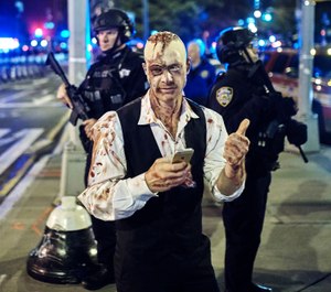 In this Oct. 31, 2017 file photo, a reveler gets his picture taken by a friend in front of heavily armed police during the Greenwich Village Halloween Parade in New York. The NYPD says thousands of uniformed and plainclothes officers will patrol the 2018 parade in Greenwich Village. They'll be joined by counterterrorism units, police dogs and helicopters. (AP Photo/Andres Kudacki, File)