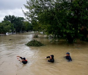 People wade through chest deep water down Pine Cliff Drive as Addicks Reservoir nears capacity due to near constant rain from Tropical Storm Harvey in Houston.