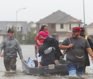 Fran Cuong, second from left, shields his daughter from wind and rain as he and his family are rescued by Mason Broussard, left, Edrick Browne, right, and a third man, in rising floodwaters.